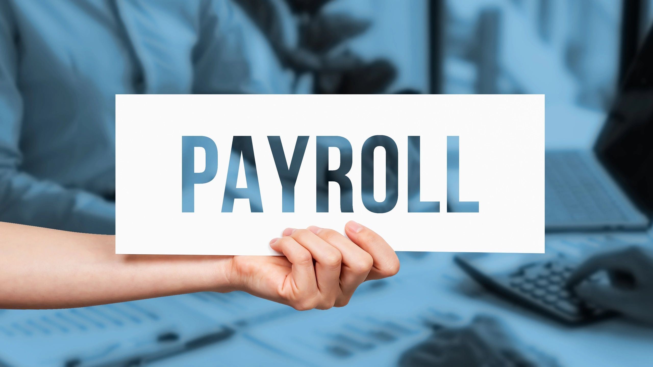 Hand holding payroll sign
